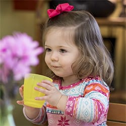 Toddler girl with cup and flowers